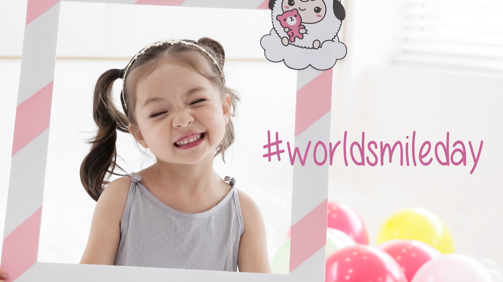 Happy child celebrating World Smile Day posing with a themed photo frame.