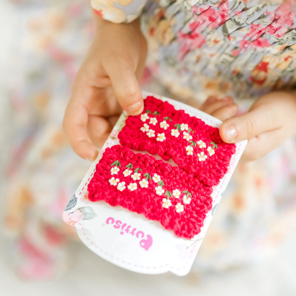 Hand holding pink floral crochet hair clips.