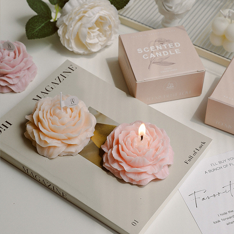 Peonie flower soy wax candle by Jellycup, styled on a book with a pink box.