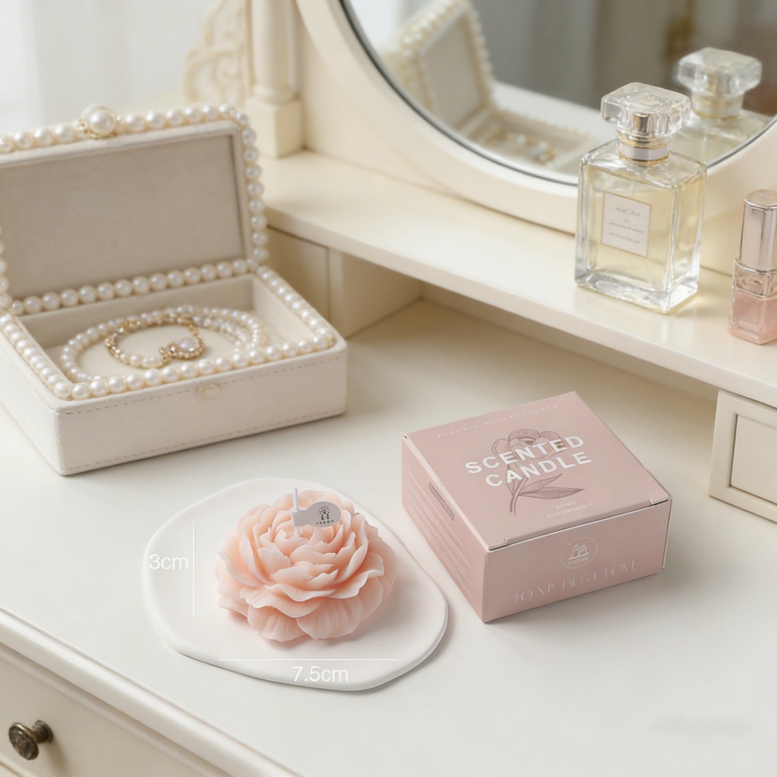 Peonie flower soy wax candle by Jellycup, on a white ceramic dish beside a light pink box.