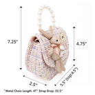 A pink tweed purse with a pearl handle and a bunny decoration.