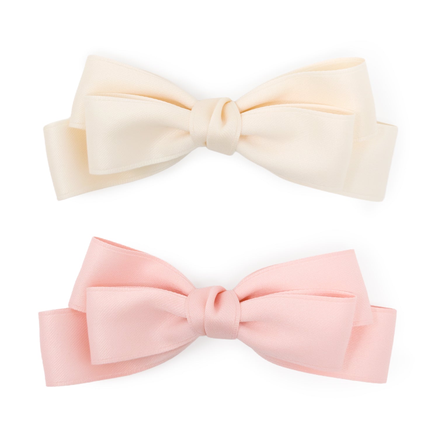 A set of two large satin double bow clips in blush and ivory, with a smooth texture.