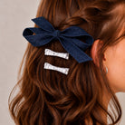Denim and silver bow clip set with one large denim bow and two small silver bows in wavy brown hair.