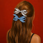 Light denim and silver bow clip set styled in wavy brown hair against a red background.