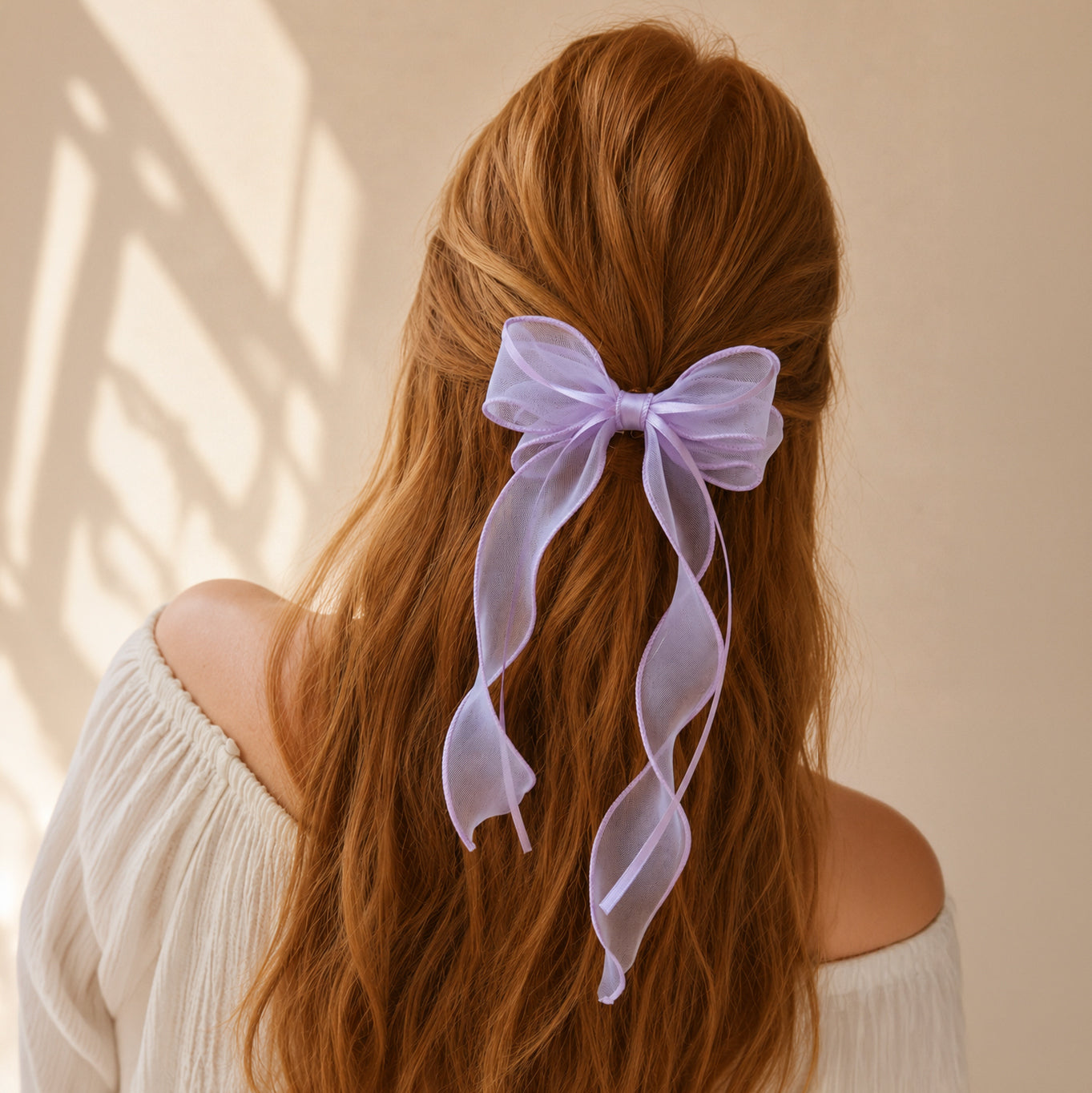 Light purple organza double ribbon clip with long, sheer flowing ends, worn in wavy red hair from the back.