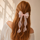 Pink sheer organza double ribbon bow clip worn in reddish-brown hair with long flowing ribbons.