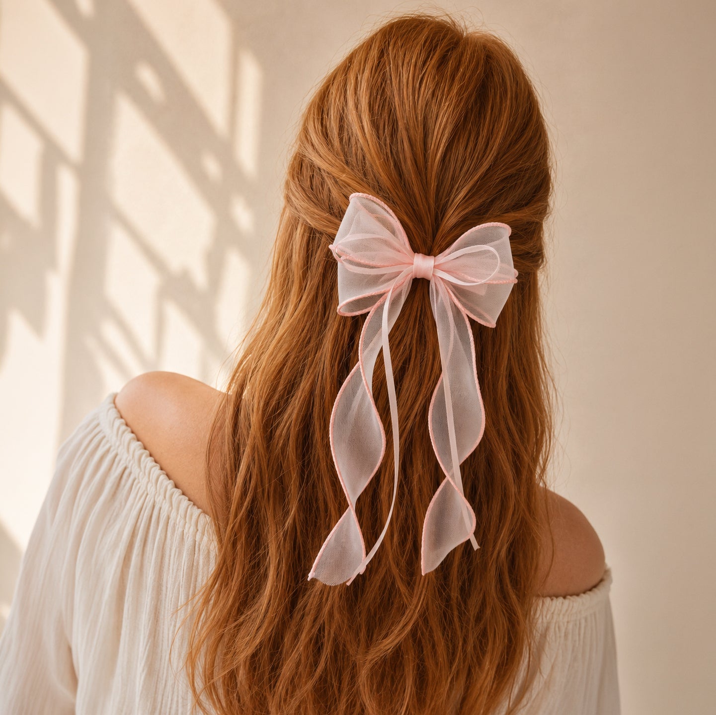 Pink sheer organza double ribbon bow clip worn in reddish-brown hair with long flowing ribbons.