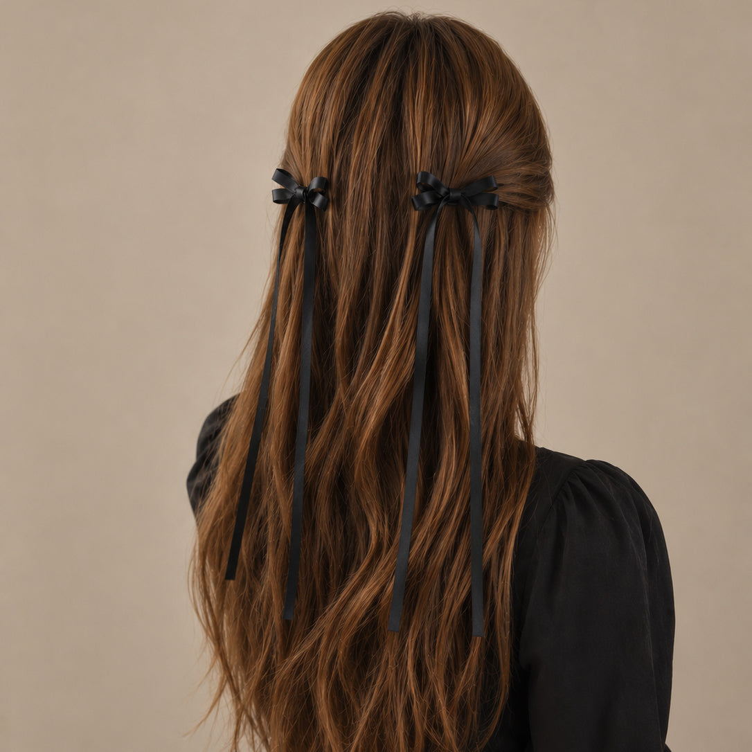 Black ribbon bow clip set featuring two bows on each side with long trailing ribbons, worn in wavy brown hair.