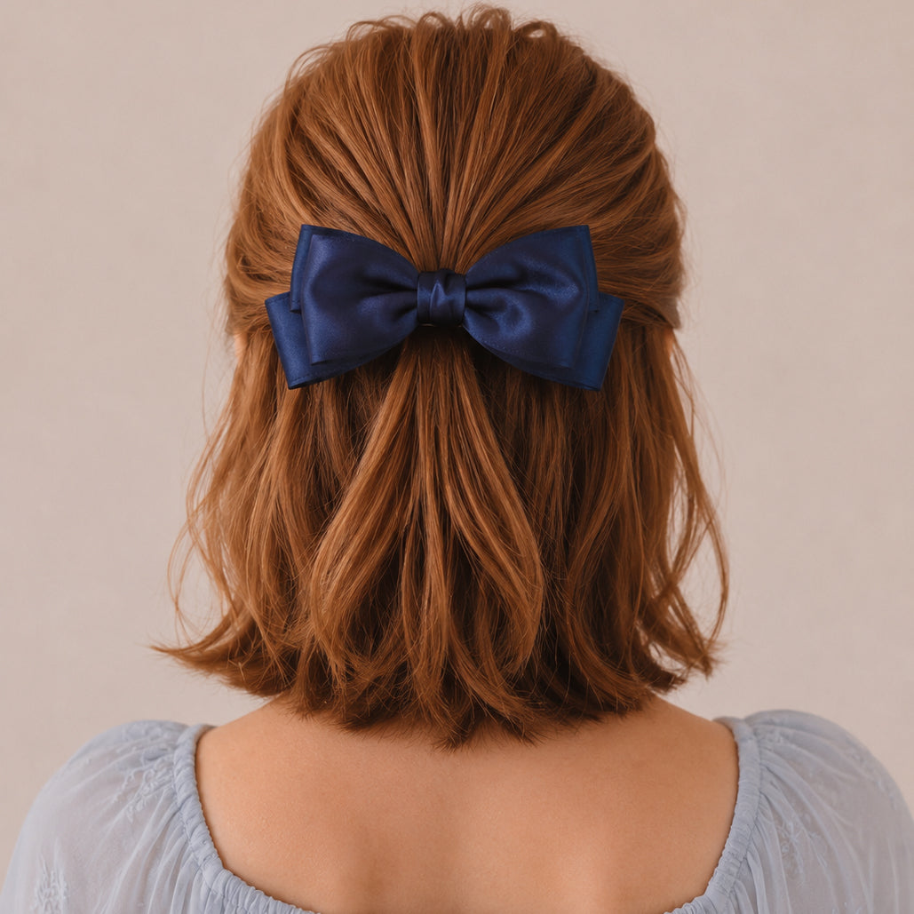 A large navy satin double bow clip on reddish-brown hair.