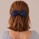 A large navy satin double bow clip on reddish-brown hair.