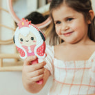 Young girl holding a pink cartoon princess comb.