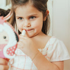 Girl applying lipstick while looking in a cartoon-shaped mirror.