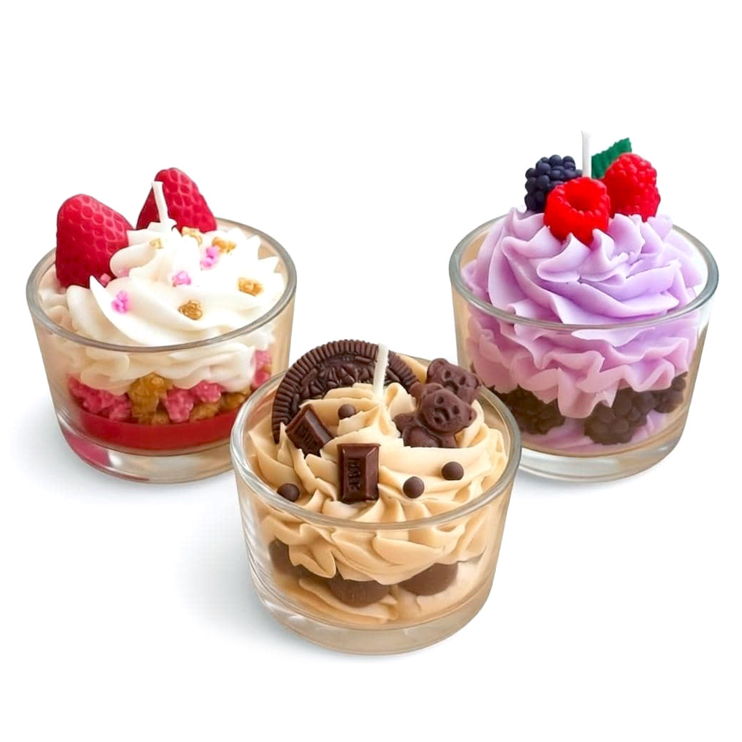 Three Jellycup sox wax candles designed to look like dessert parfaits in clear glass cups, each topped with piped whipped-style wax and decorative accents—strawberries and sprinkles on a vanilla design, chocolate cookies and pieces on a caramel design, and mixed berries on a lavender design.